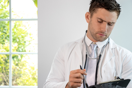 Good looking male doctor, gp, with stethoscope and clipboardの写真素材
