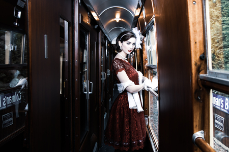 Beautiful woman dressed in red tea vintage tea dress on locomotive trainの写真素材