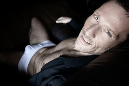 Good looking middle aged man wearing underwear and an open shirt looking at cameraの写真素材