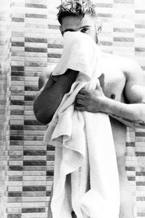 Good looking man towelling himself dry in showerの写真素材