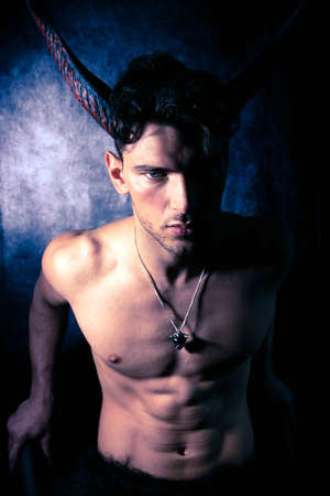 Sexy shirtless male devil with horns and muscular body showing pecs and abs looking at cameraの写真素材
