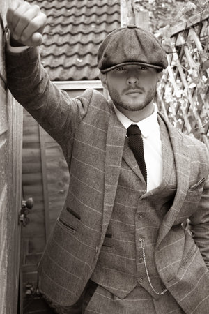 Handsome English gangster leaning on brick wall in back streets of birminghamの写真素材
