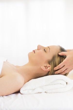 Side view of relaxed young woman receiving head massage at health spaの写真素材