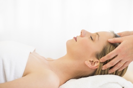 Side view close-up of beautiful young woman receiving head massage at health spaの写真素材