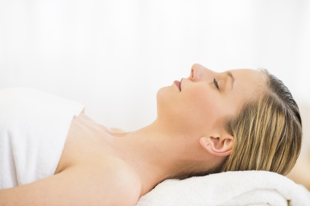 Side view close-up of beautiful young woman resting on massage table in health spaの写真素材