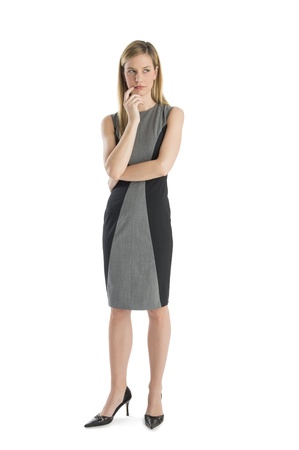 Full length of thoughtful young businesswoman with hand on chin looking away isolated over white backgroundの写真素材