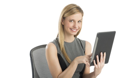 Portrait of beautiful young businesswoman using digital tablet while sitting on chair against white backgroundの写真素材