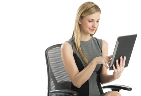 Beautiful young businesswoman using digital tablet while sitting on chair against white backgroundの写真素材