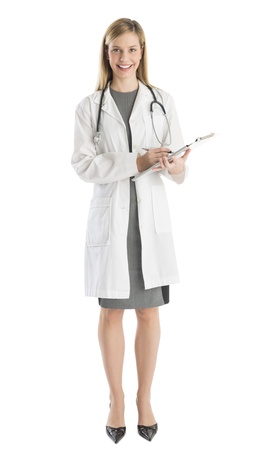Full length portrait of happy female doctor with clipboard and stethoscope standing against white backgroundの写真素材