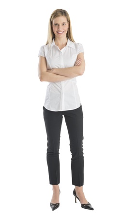 Full length portrait of young businesswoman smiling while standing arms crossed isolated on white backgroundの写真素材