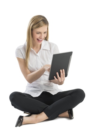 Full length of happy young businesswoman using digital tablet while sitting on floor isolated on white backgroundの写真素材