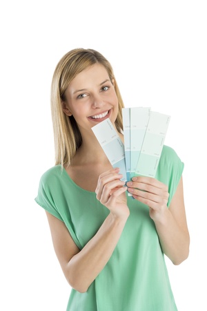 Portrait of happy young woman holding color swatches against white backgroundの写真素材
