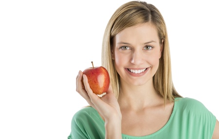 Portrait of beautiful young woman smiling while holding apple against white backgroundの写真素材