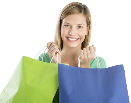 Portrait of young woman holding shopping bags while smiling isolated over white backgroundの写真素材