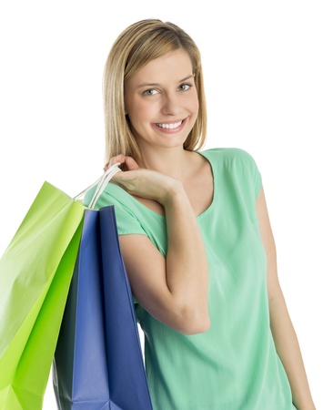 Portrait of beautiful young woman carrying shopping bags against white backgroundの写真素材