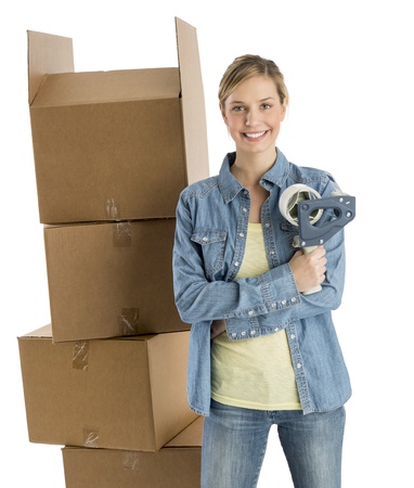 Portrait of beautiful young woman with adhesive tape standing by stacked cardboard boxes against white backgroundの写真素材