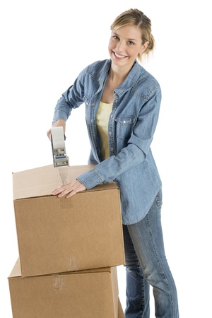 Portrait of happy young woman taping cardboard boxes against white backgroundの写真素材