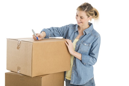 Young woman writing on cardboard boxes isolated over white backgroundの写真素材