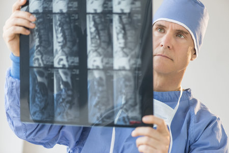 Mature male surgeon examining X-ray report in hospital