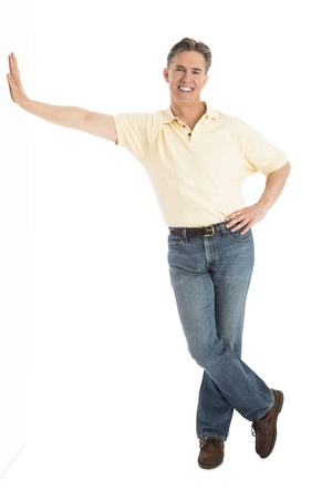 Full length portrait of happy mature man in casuals leaning over white backgroundの写真素材