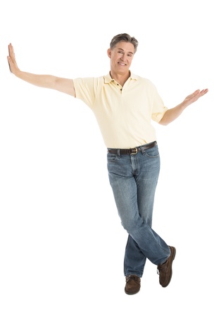 Full length portrait of happy mature man in casuals gesturing while leaning over white backgroundの写真素材