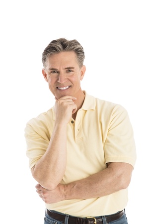 Portrait of handsome mature man with hand on chin standing over white backgroundの写真素材