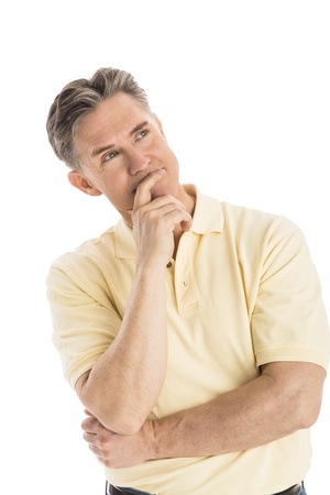 Thoughtful mature man with hand on chin looking away while standing over white backgroundの写真素材