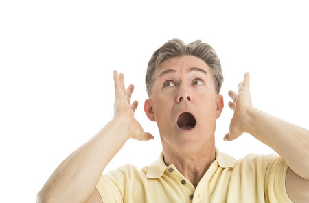 Close-up of fearful mature man looking up while gesturing against white background