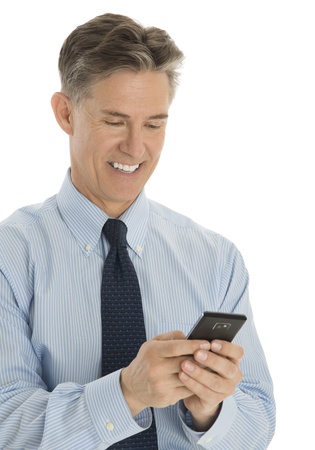 Happy mature businessman texting through smart phone over white backgroundの写真素材