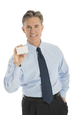 Portrait of confident mature businessman showing blank business card against white backgroundの写真素材