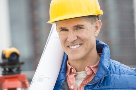 Close-up portrait of confident male architect with blueprint at construction siteの写真素材