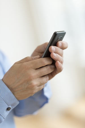 Cropped image of businessman's hands using smart phone in officeの写真素材