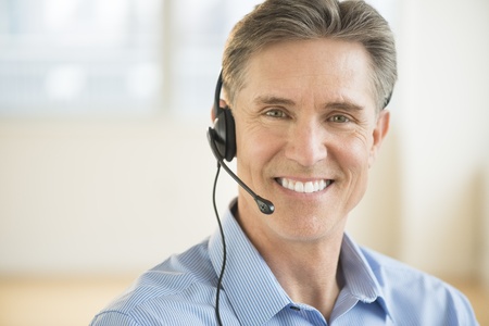 Portrait of happy mature male customer service representative wearing headsetの写真素材