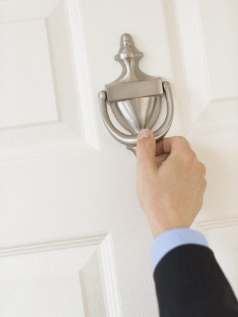 Cropped image of mature businessman's hand knocking door handleの写真素材