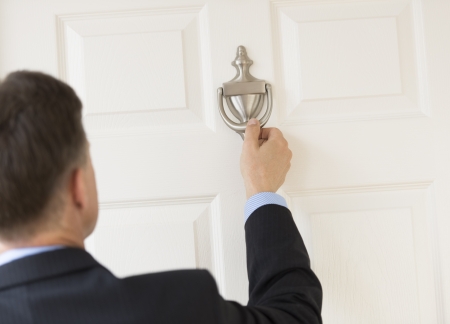 Rear view of mature businessman knocking door knockerの写真素材