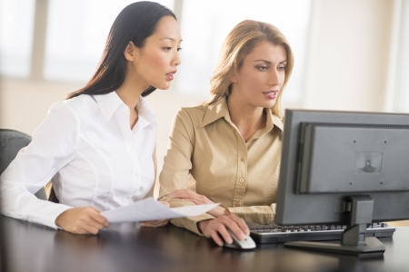 Multi-ethnic businesswomen using Desktop PC together in officeの写真素材