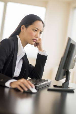 Mid adult businesswoman using Desktop PC at desk in officeの写真素材