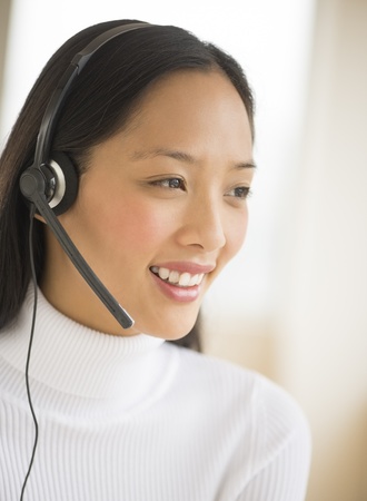 Happy female customer service representative wearing headset looking awayの写真素材