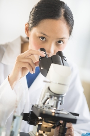 Portrait of Asian mid adult female scientist using microscope in laboratoryの写真素材