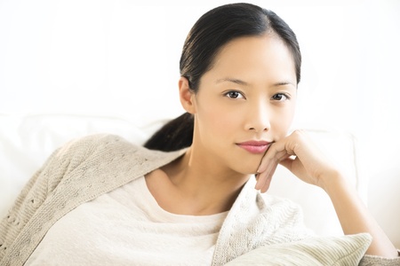 Portrait of beautiful mid adult woman smiling while relaxing on sofa at homeの写真素材