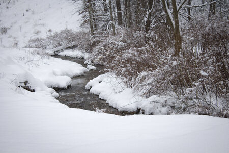 A Small Stream runs through inches of snowの写真素材
