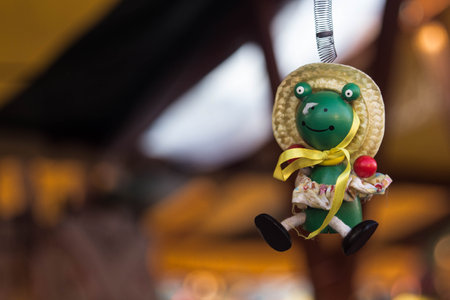 Cute frog doll with hat hanging by a springの写真素材
