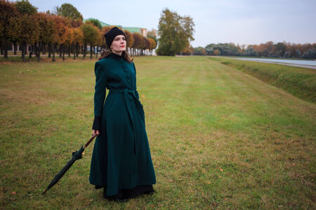 Beautiful vintage style woman with umbrella in autumn parkの写真素材