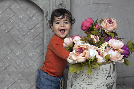 Adorable smiling little boy with flowers by the fireplaceの写真素材