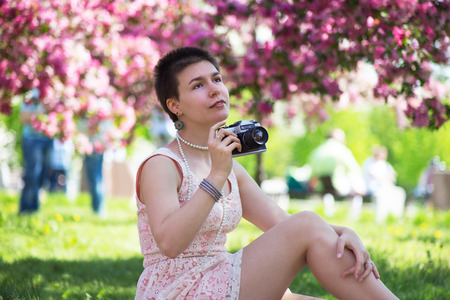 Beauty girl in park under pink flowers in summer taking pucturesの写真素材