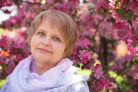adult woman wearing shawl under pink flowers in summerの写真素材