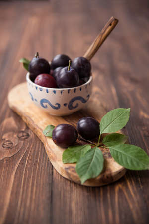Plums with leaves and napkin on wooden table. Selective soft focusの写真素材