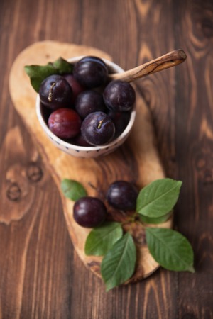Plums with leaves and napkin on wooden table. Selective soft focusの写真素材