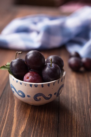 Plums with leaves and napkin on wooden table. Selective soft focusの写真素材