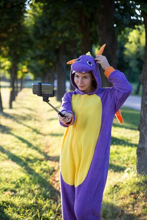 Girl wearing a carnival costume of dragon taking selfie in a parkの写真素材